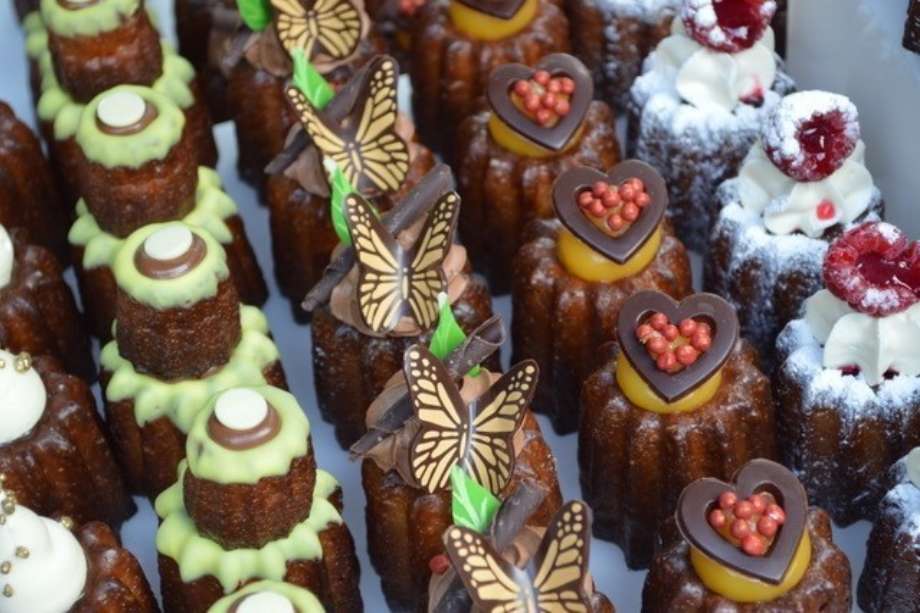 Lines of Caneles with different colourful toppings.